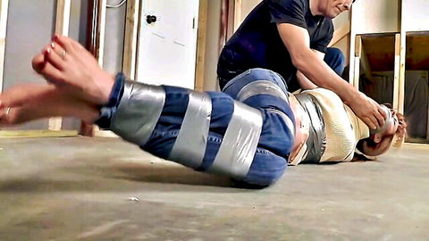 Blonde woman duct-taped bound by man in BDSM bondage tease