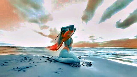 Ethereal blue painted nude woman with big tits poses seductively on sunset beach