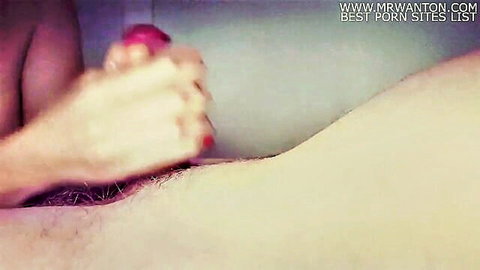 Hand gripping red vibrator near hairy pubic area in intimate tease