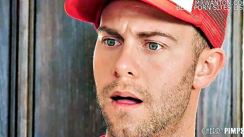 Close-up of handsome man with green eyes, stubble, open mouth, wearing red baseball cap
