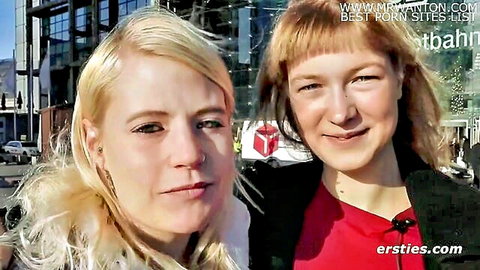 Smiling blonde and ginger German lesbians posing clothed in public street tease