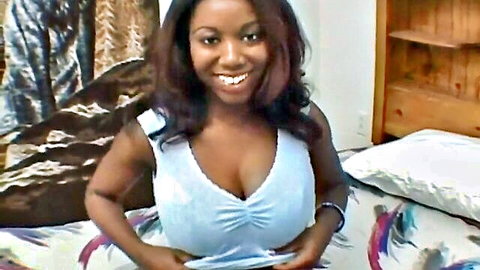 Busty ebony teen smiling in low-cut white tank top showing deep cleavage