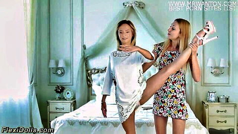 Flexible twin dolls stretching seductively in short dresses, one lifting the other's leg high