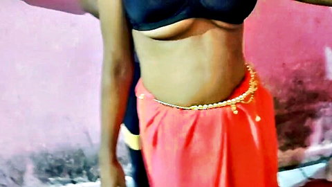 Indian woman topless in open black bra, pink wrap skirt, gold waist chain