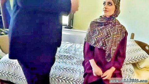 Arab woman in hijab and purple dress sits on bed with suited man