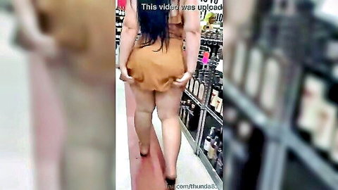 Curvy Latina dancing in short dress in supermarket aisle
