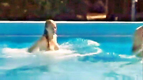 Blonde nudist with large breasts splashing in outdoor pool