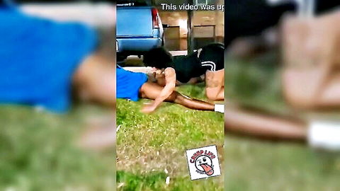 Outdoor interracial gay sex scene with athletic black man in black shorts and partner in blue top on grass