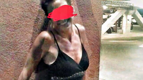 Ebony mature wife in tight black dress flashing deep cleavage smiling in parking garage
