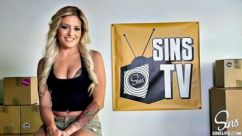 Smiling blonde with tattoos in cleavage-baring tank top and shorts on SinsLife set