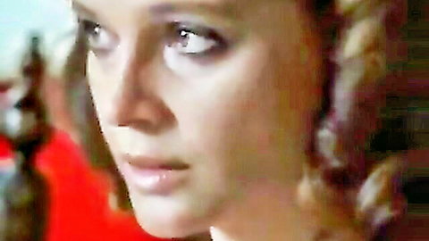 Closeup of sensual curly blonde woman with intense gaze and plump lips in erotic movie scene