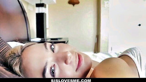 Blair Williams smiling seductively in bed, teasing in white tank top