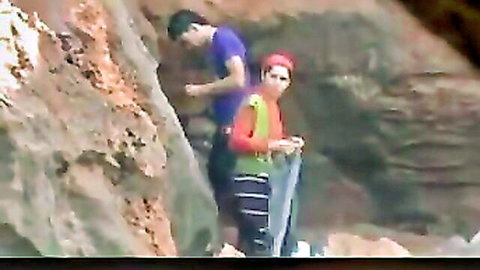 Outdoor anal scene with couple, man assisting woman in rocky terrain