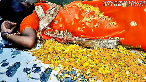 Sexy Indian woman in red saree lying on bed of yellow marigold flowers