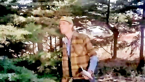 Handsome white guy in plaid flannel shirt and cap walks in lush forest, outdoor vibe