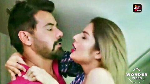 Bearded Indian man passionately kissing sexy blonde woman with red lips in intense embrace