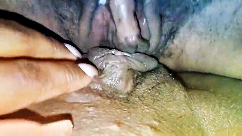 Close-up of aroused pussy with clitoris exposed, fingers spreading labia and cum visible