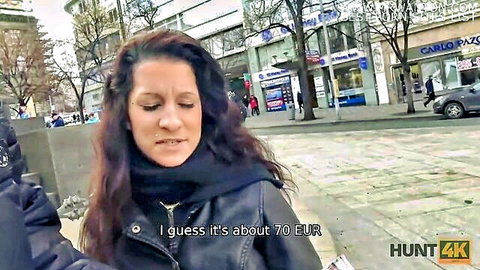 Curly brunette in leather jacket on busy street guessing 70 EUR price in Hunt4K public pickup video