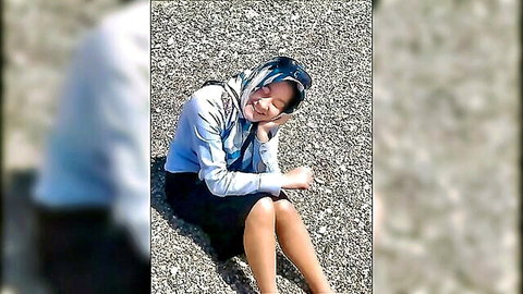Playful hijabi girl in skirt teases smiling on pebble beach