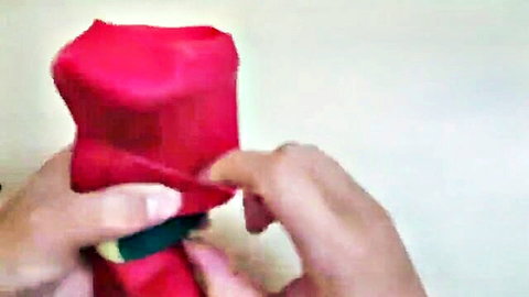 Hands unwrapping a red gift box revealing green ribbon inside