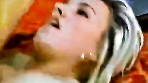 Blonde woman with open mouth in intense oral sex scene on bed
