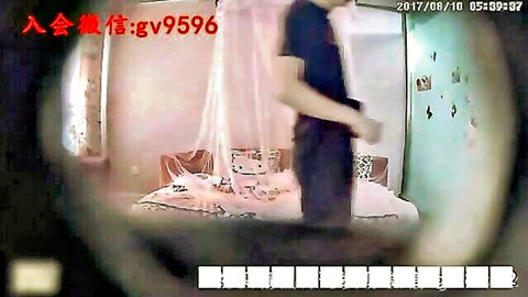 Amateur Asian man in black shirt standing by bed in hotel room, woman in white nearby