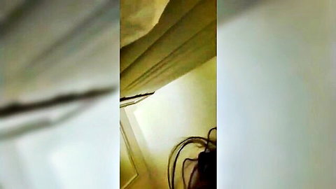 Blurry empty bedroom corner with beige curtains draped over window and black cables on floor