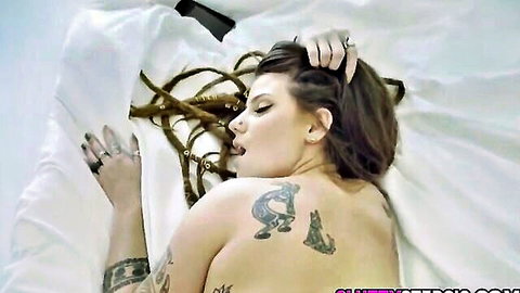 Indica Flower with braids and tattoos lies nude seductively on bed