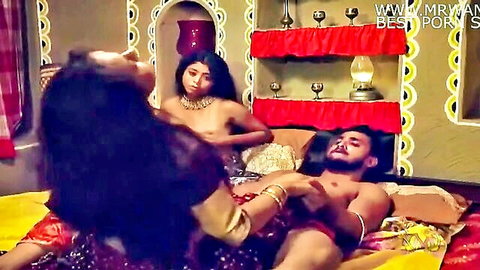 Topless Indian woman straddles muscular man's hard cock while another watches passionately.