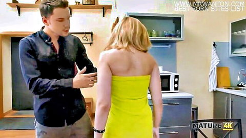 Blonde mature in yellow dress touched by angry man in kitchen scene