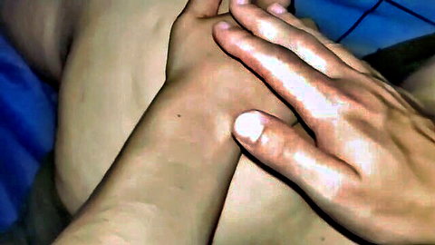Closeup of hands gripping and spreading smooth pale thighs on blue bed