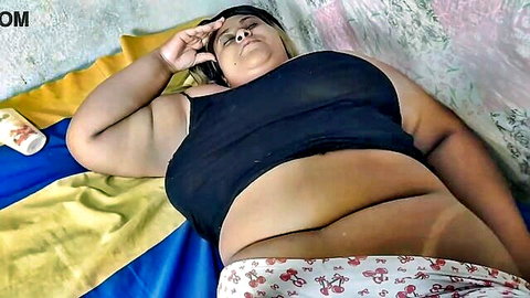 Curvy Indian BBW stepmom lounging seductively in black tank top and pink panties