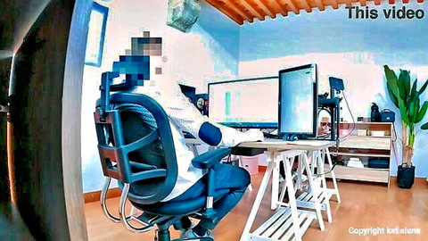 Hidden camera view of secretary sitting at office desk with dual monitors