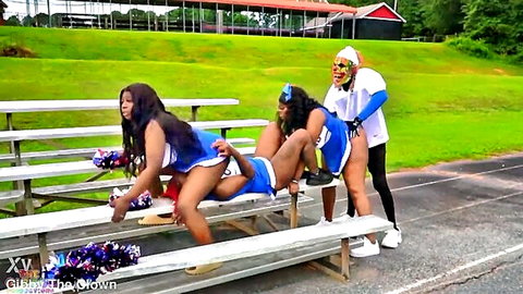 Black cheerleaders in blue uniforms doing flexible splits outdoors with clown
