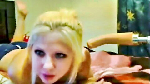 Skinny blonde with small tits lies topless on bed holding huge tan dildo at her crotch seductively