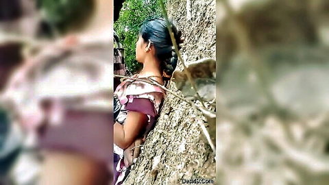 Telugu woman in purple saree posing against rock wall outdoors