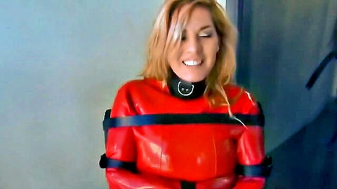 Blonde woman bound in red latex straitjacket BDSM pose
