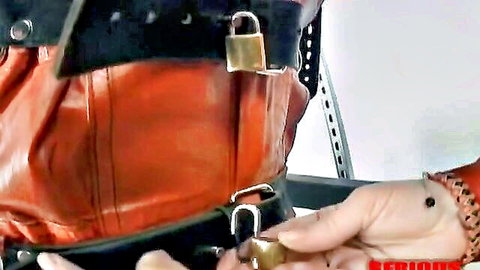 Woman in red leather BDSM harness locked with padlocks, bondage kink scene