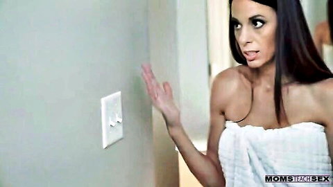 Brunette stepmom in towel gesturing at light switch in Moms Teach Sex teaser
