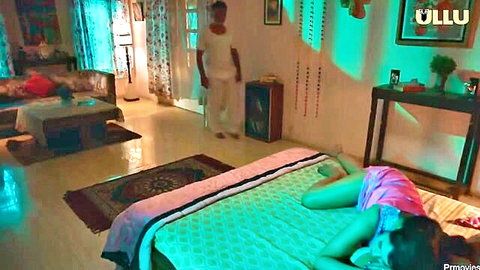 Desi MILF in pink nightie lying prone on bed, teasing pose with man behind
