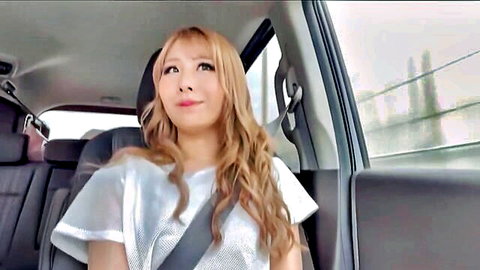 H-cup blonde JAV gal in sheer top smiling in car seat