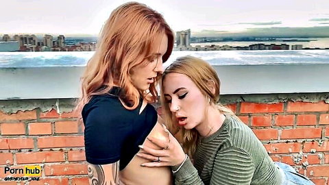 Redhead and blonde lesbians exposing breasts and playing on rooftop
