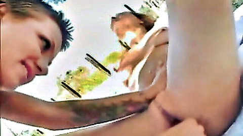 Two women in close lesbian embrace outdoors, short red hair on one