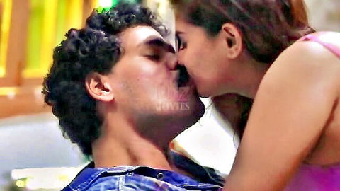 Indian couple in passionate kiss, woman in pink top on man in denim jacket