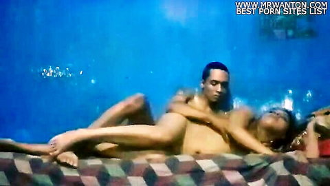 Nude Asian couple in spooning embrace, intimate bedroom moment