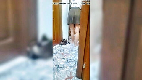 Amateur woman in short gray skirt, bare legs and feet in doorway tease
