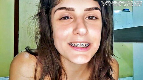 Young Latina girl with butterfly braces smiling, close-up face shot