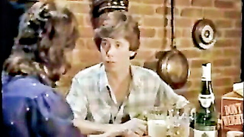Vintage couple scene from Private Teacher adult film, woman in blue top and man in plaid shirt chatting