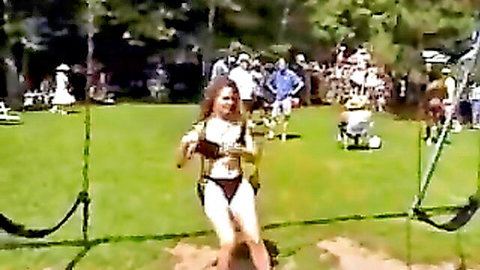 Topless brunette in bikini harness at nudist rally outdoor event