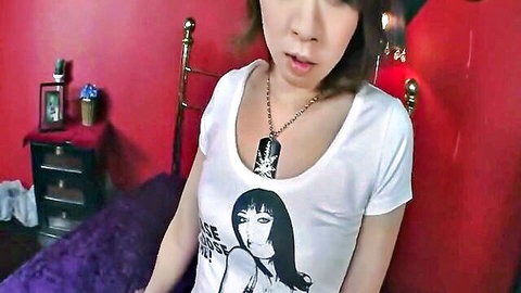 Cute Japanese girl in white Grace t-shirt with necklace posing seductively on purple bed sheets